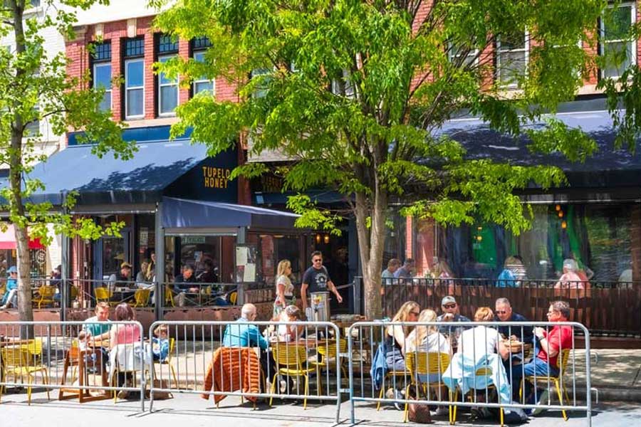 People enjoying their meal on an outdoor dining area in Tupelo Honey Cafe