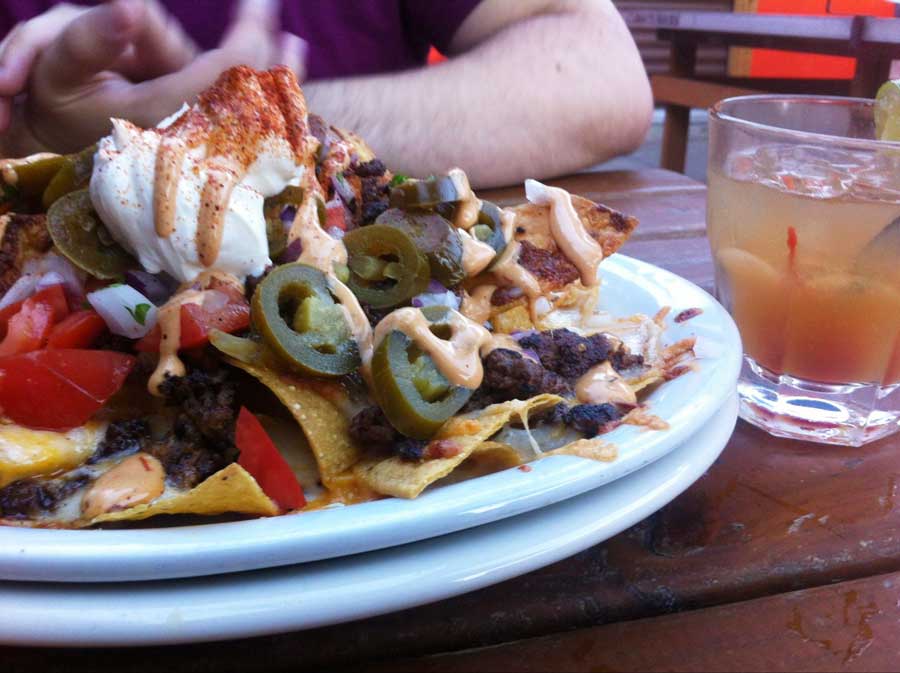 A nachos filled with toppings on a plate in Twilight Exit