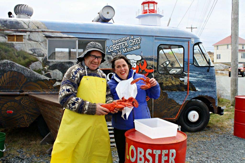 Man and woman posed with lobsters with van on background at Peggy's Cove Nova Scotia