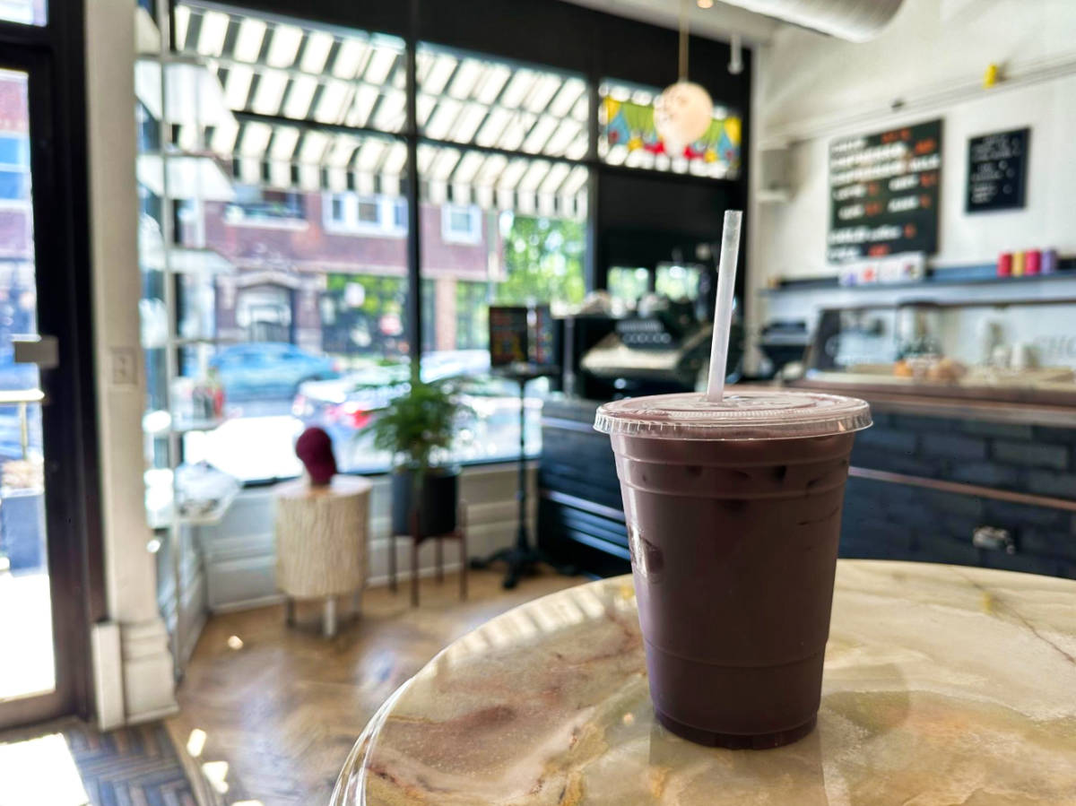A cup of ube oat milk latte on the table at Four Letter Word Coffee