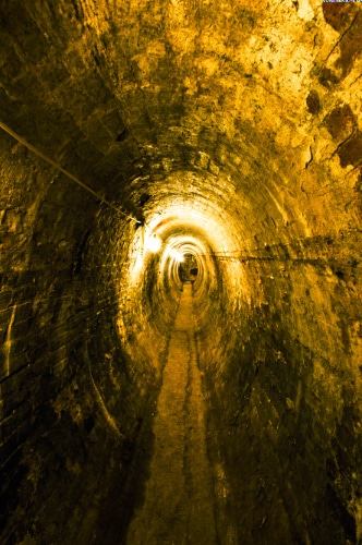 View of the narrow underground tunnel with yellow lights inside