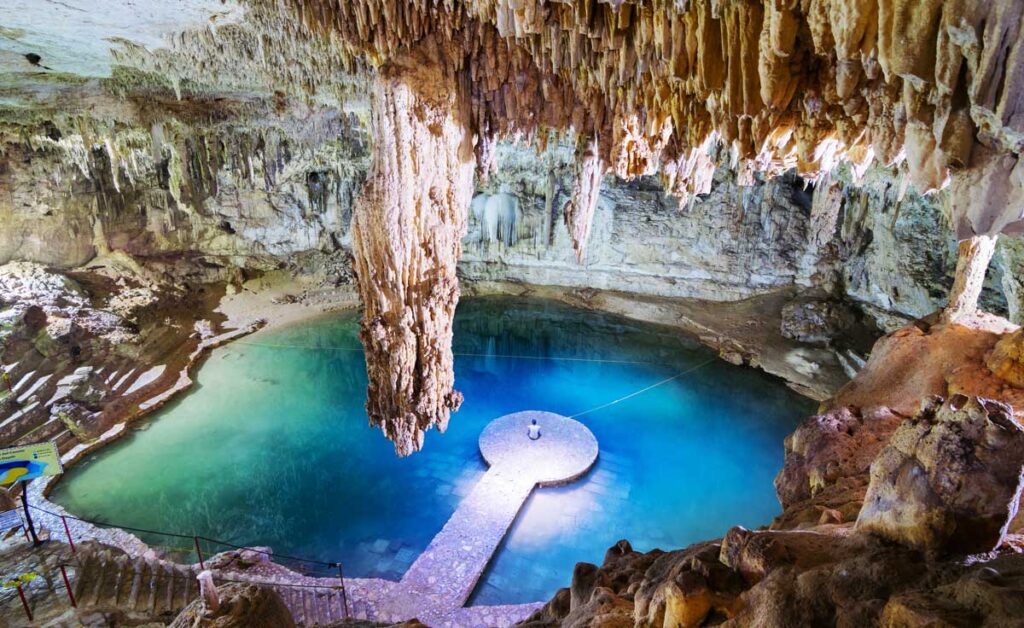 View of a man sitting in the middle of Valladolid’s Cenote Suytun
