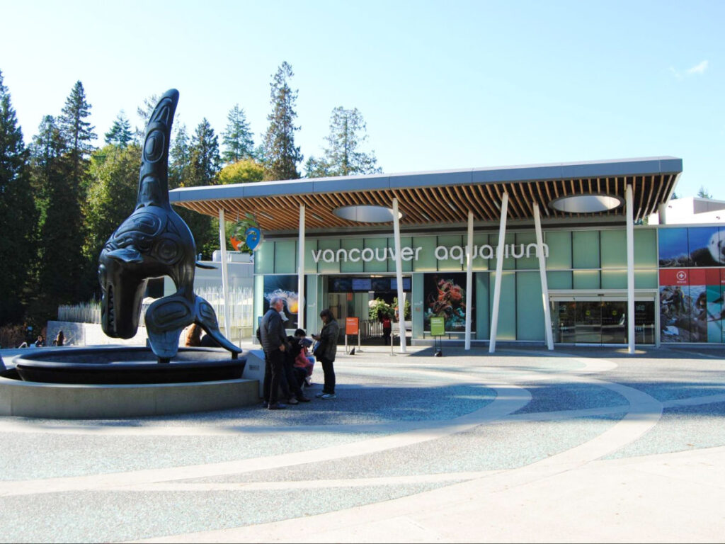 View of thee people chilling near the sculpture in front of the Vancouver Aquarium