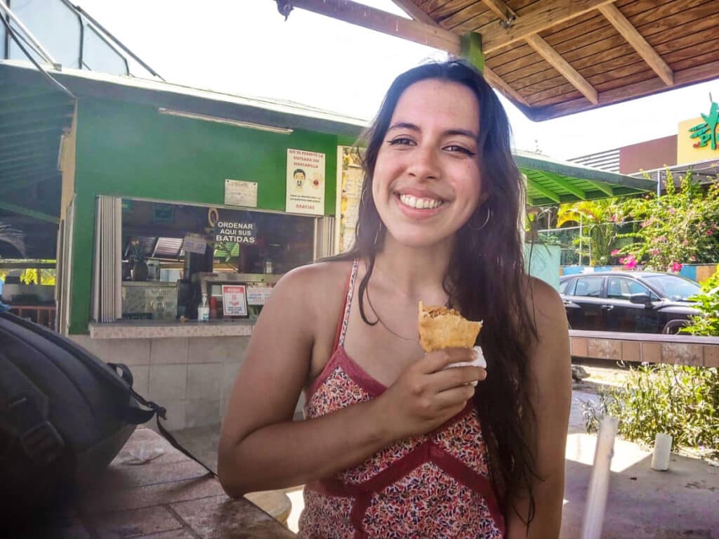The author Vanessa Ramos, eating the chicken-filled fritters at Piñones