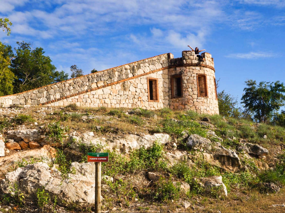 The author Vanessa Ramos, posing on top of the Fuerte Caprón and the clear blue sky above it