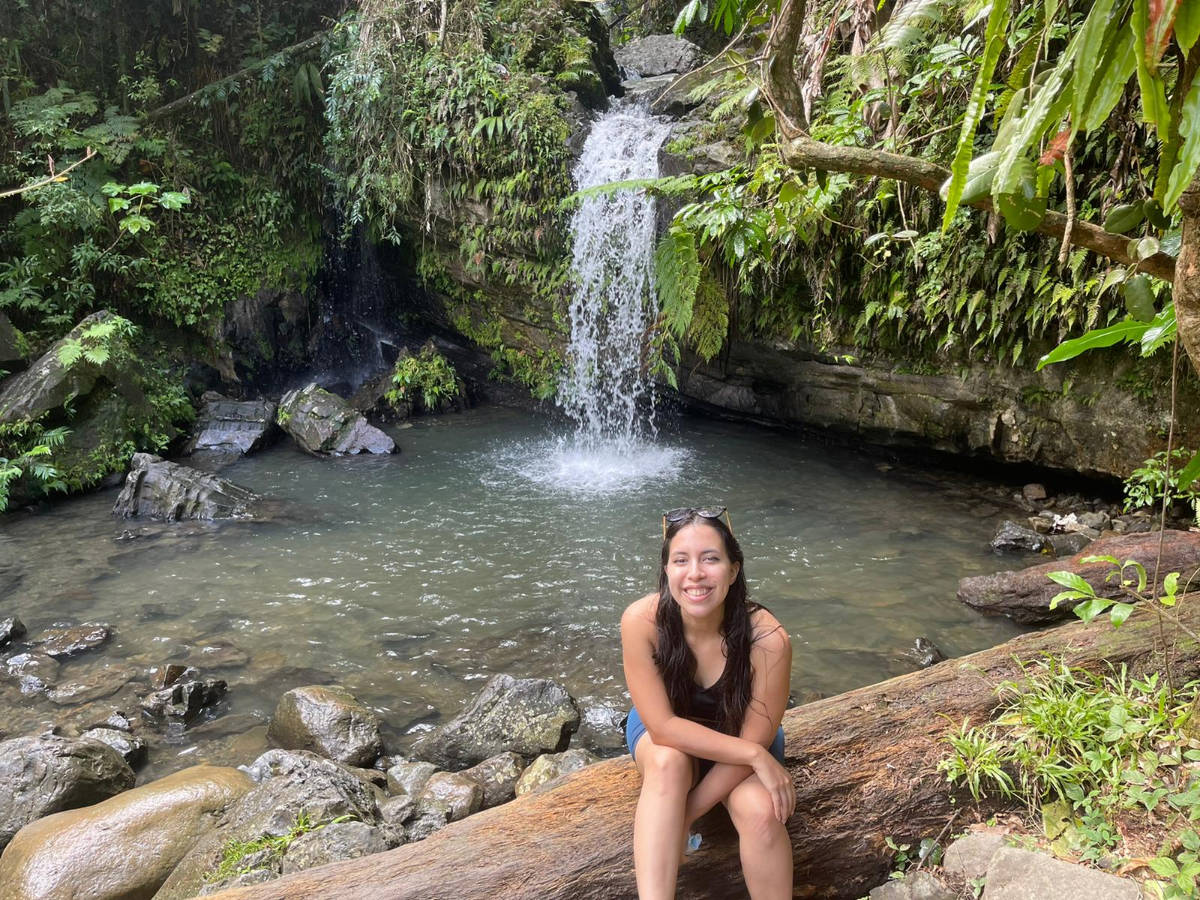The author, Vanessa Ramos smiling for a photo with the Juan Diego Falls on her background