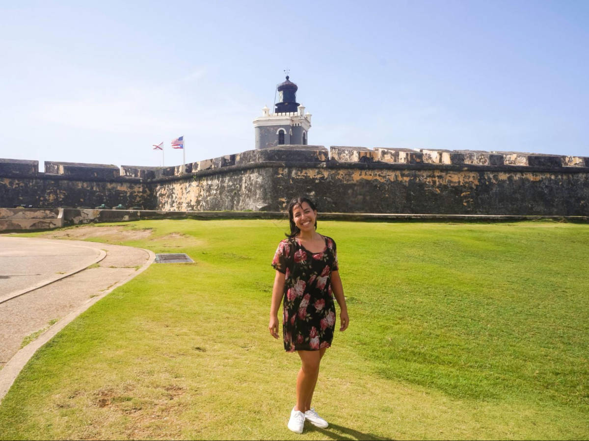 The author Vanessa Ramos posing for a photo on the grass field at Castillo San Felipe del Morro