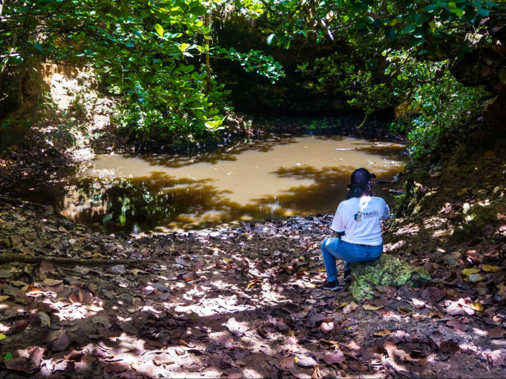 The author Vanessa Ramos, sitting on a rock overlooking the water at Pozo Brujo