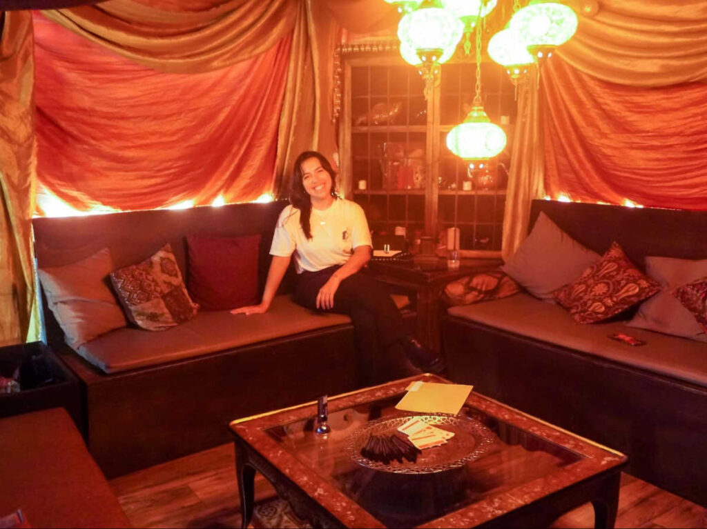 The author Vanessa Ramos sitting inside the dim lit Scryer Rum