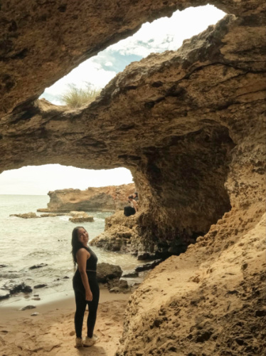 The author Vanessa Ramos posing for a photo inside a cave at the beach