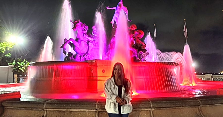 The author Vanessa Ramos in front of the illuminated colorful fountain at night