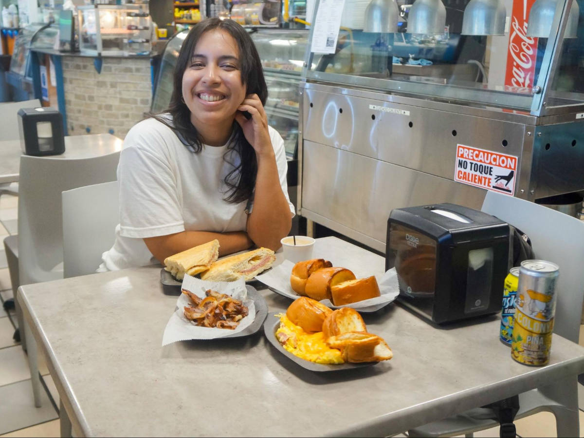 The author Vanessa Ramos sitting at a table full with local foods from a Panaderia