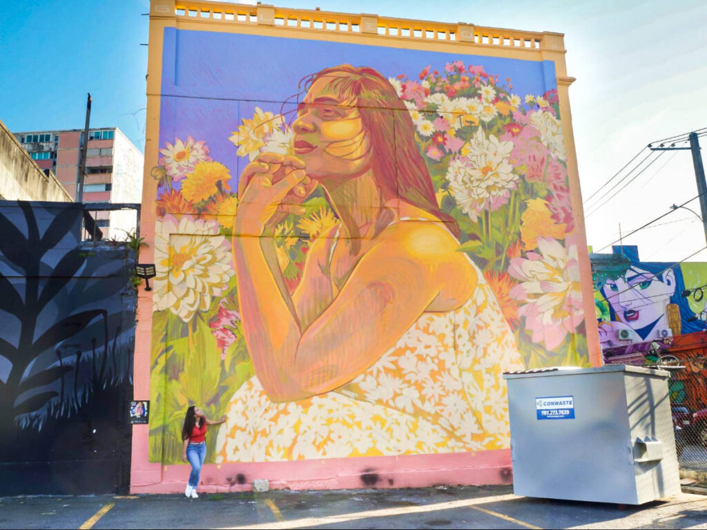 The author Vanessa Ramos posing for a photo at the bottom of the huge mural