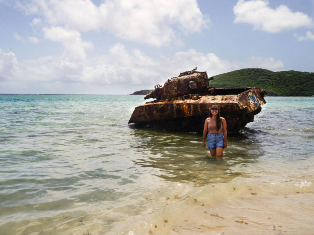 The author Vanessa Ramos, posing for a photo in front of the abandoned tank at the Flamenco Beach
