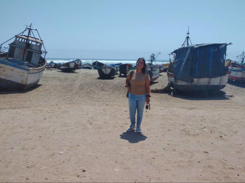 The author Vanessa standing in front of the boats in Caleta Santa Rosa