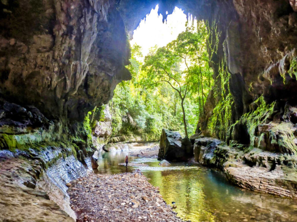 The author Vanessa Ramos, walking along the shallow water inside the Cueva del Arco, Utuado