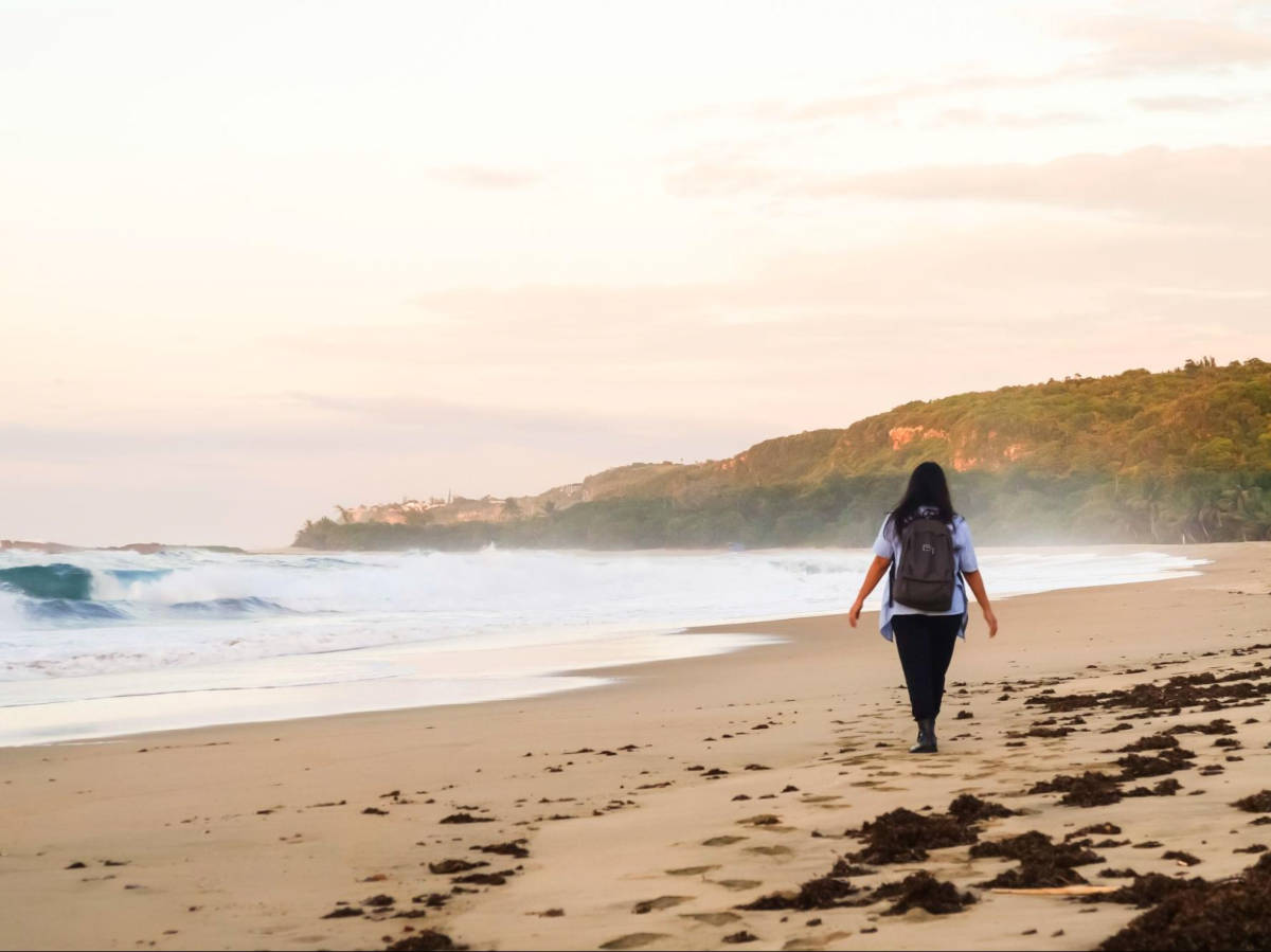 The author Vanessa Ramos, walking along the vast sandy beach of El Pastillo Beach