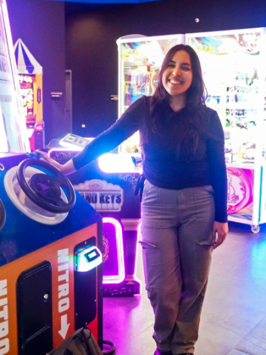 The author Vanessa Ramos, standing next to arcade game in Toro Verde’s