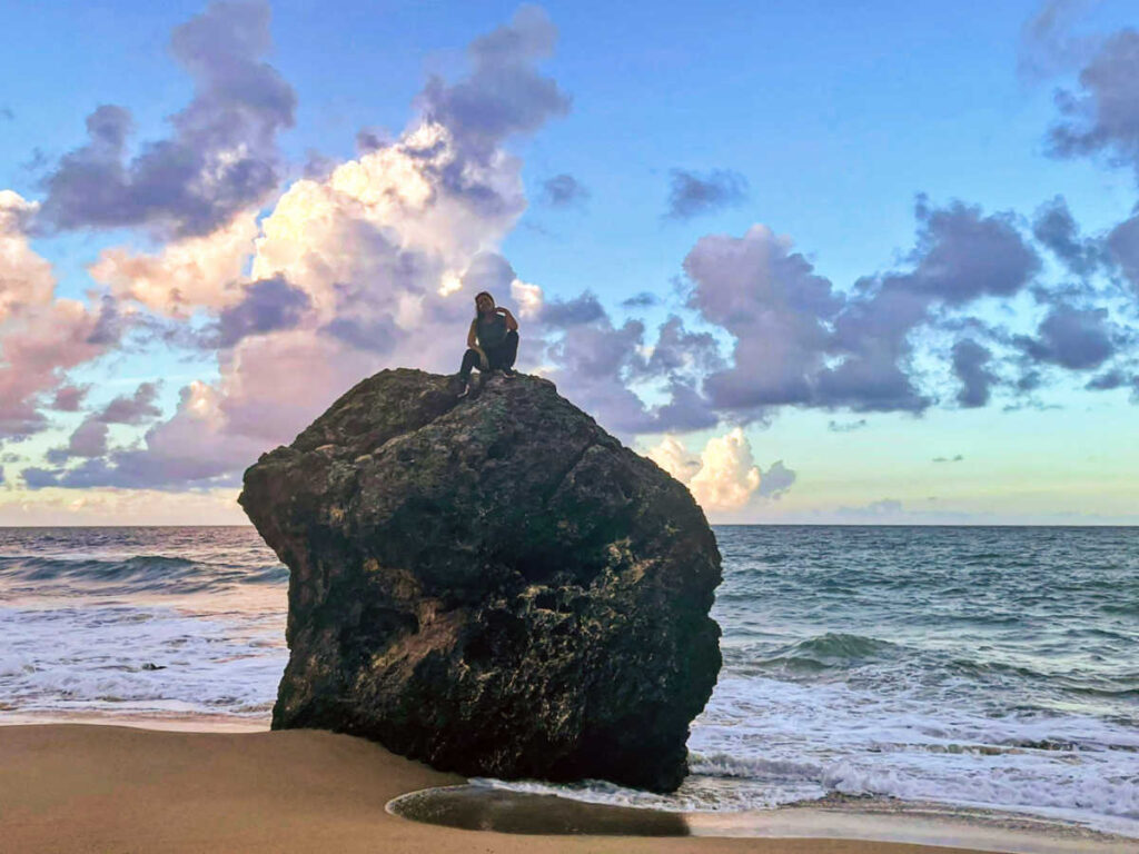 The author Vanessa Ramos, sitting on top of a huge rock in Pelicano Beach