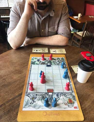 The author playing a board game with her husband in Vashon Island Coffee Roasterie