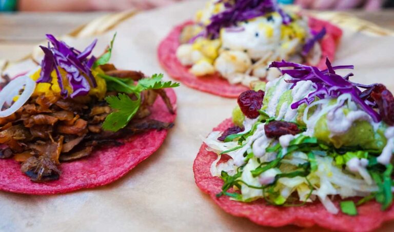 A trio of vegan tacos, each uniquely topped with vibrant ingredients