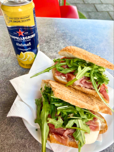 A plate with two Venezia paninis with a can of lemonade on the side