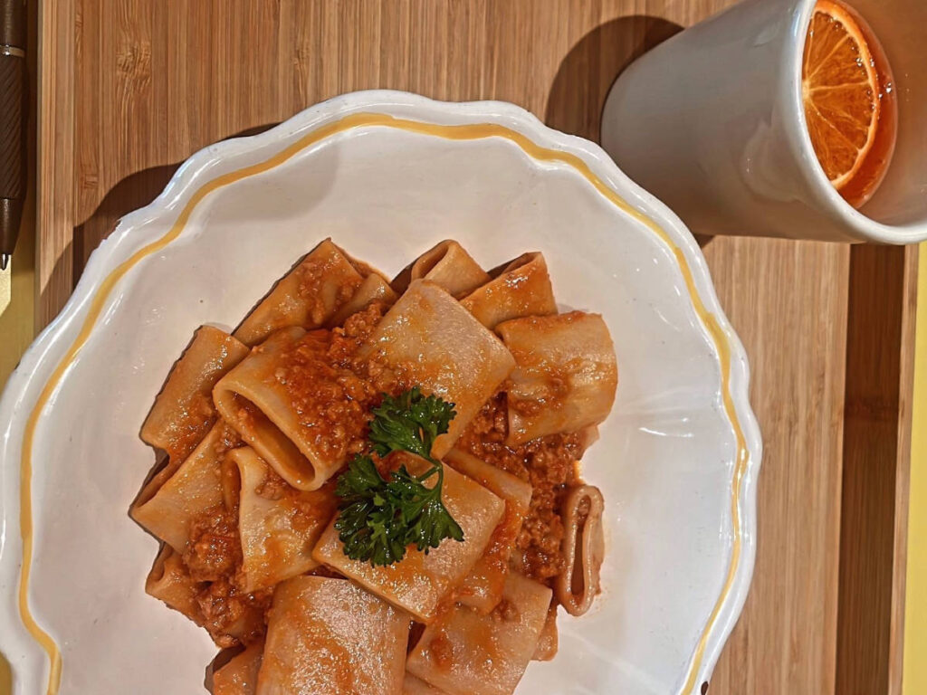 Pasta on a plate and Aperol spritz served at Via Pasteria