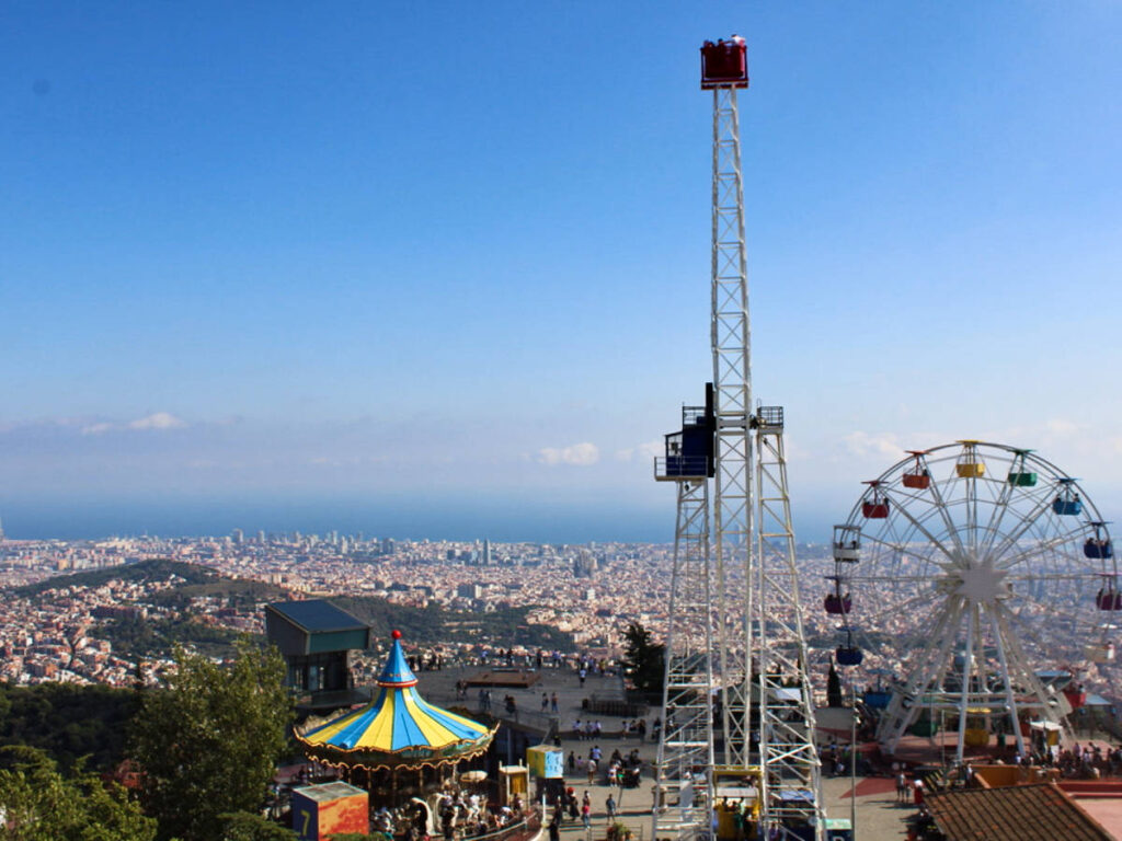 View of the Ferris wheel, carousel and other rides with an overlooking view of Barcelona from Tibidabo Amusement Park