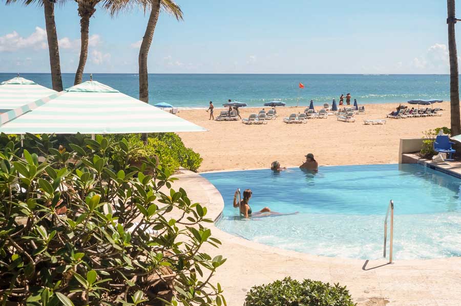 View of people in the pool and at the beach in La Concha Renaissance San Juan Resort