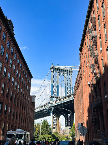 View of the Brooklyn Bridge in between the buildings seen from the street
