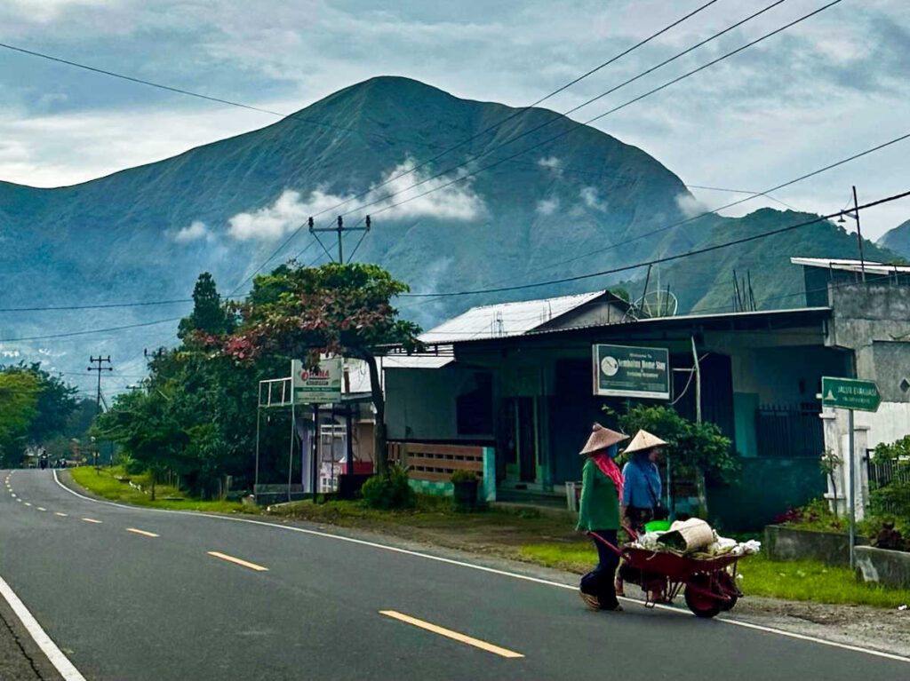 The villagers walking down the streets of Senaru with mountain views in the background