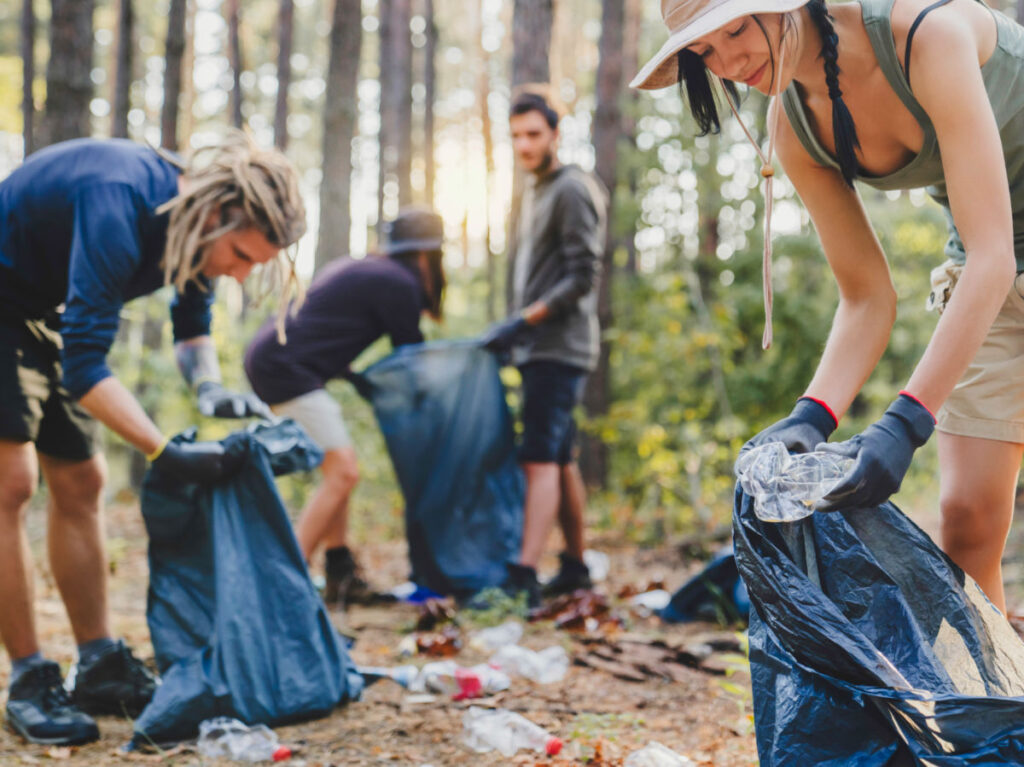 Group of young friends volunteers with trash bags, helping to clean forest