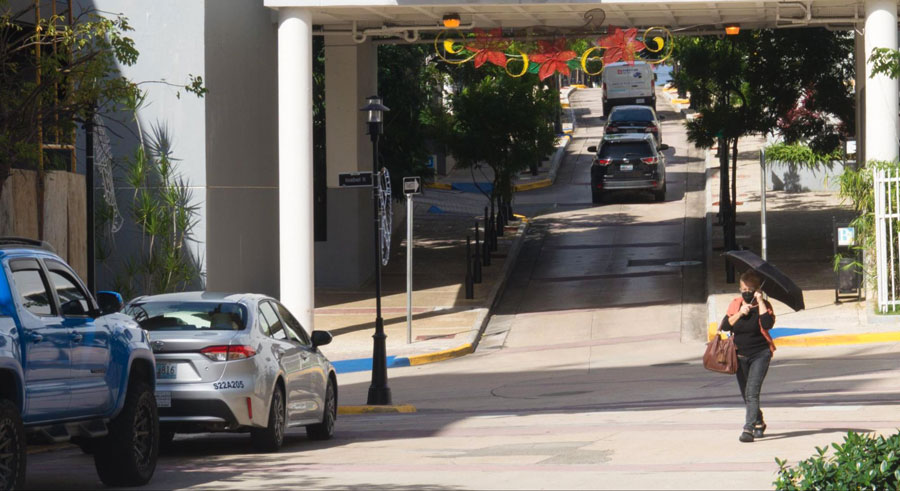 View of cars parked on the side and a woman walking with her umbrella