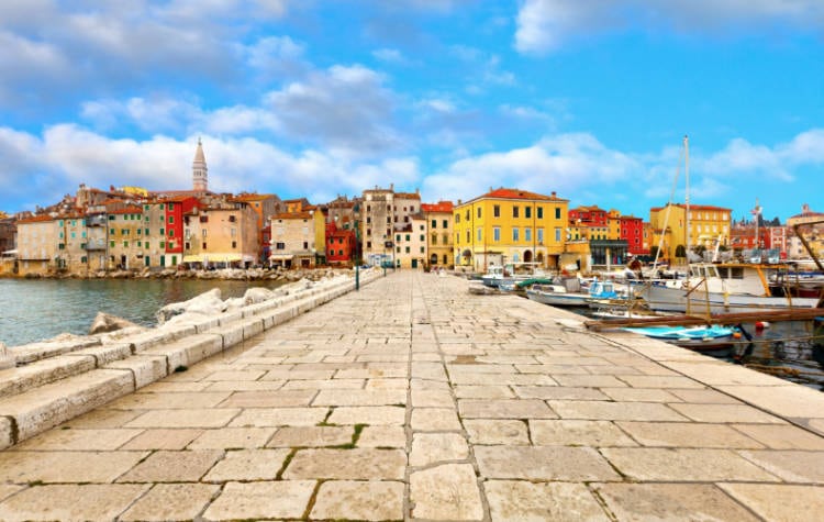 A stone walkway leading to the colorful buildings in the distance