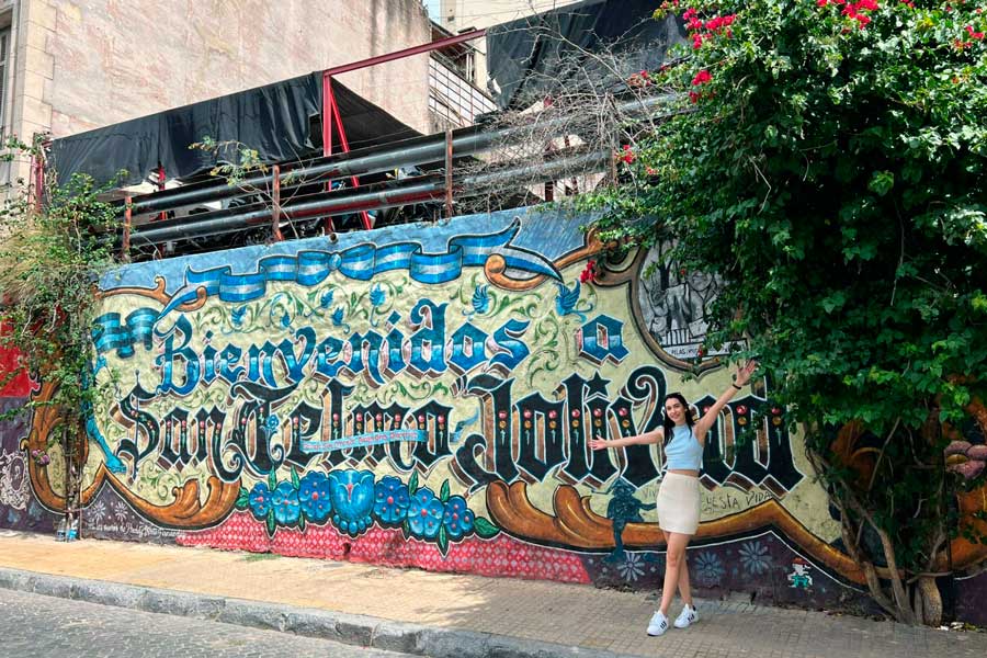 Clara posing for a photo in front of a mural in San Telmo