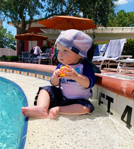 The author's son wearing a cap sitting by the pool