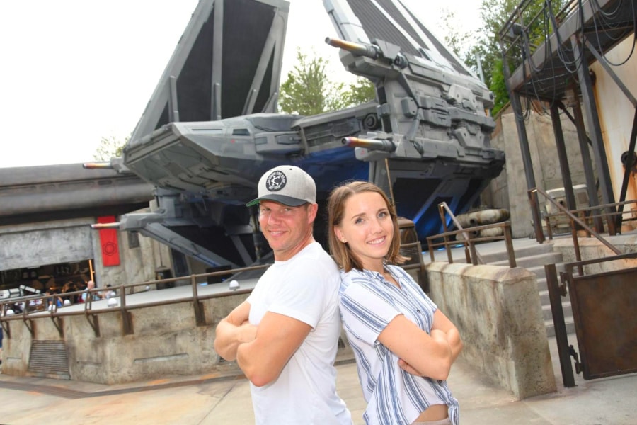 The author and her husband posing in Star Wars: Galaxy’s Edge at Disney’s Hollywood Studio, with Star Wars exhibit in background