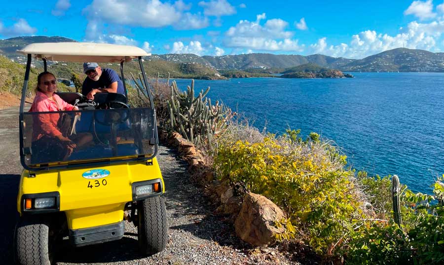 A man and a woman driving around Water Island with their golf cart