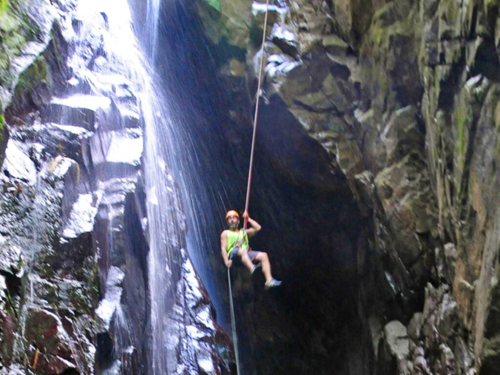 A man reppeling in the middle of the waterfalls