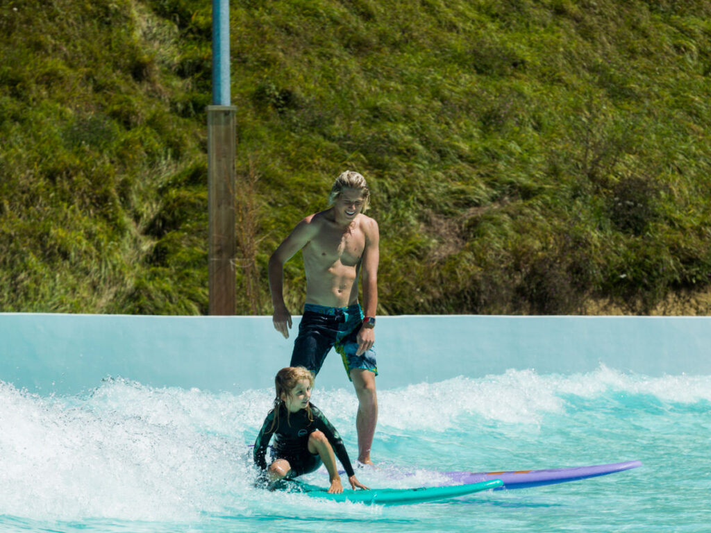 A man and a child enjoy wave pool surfing