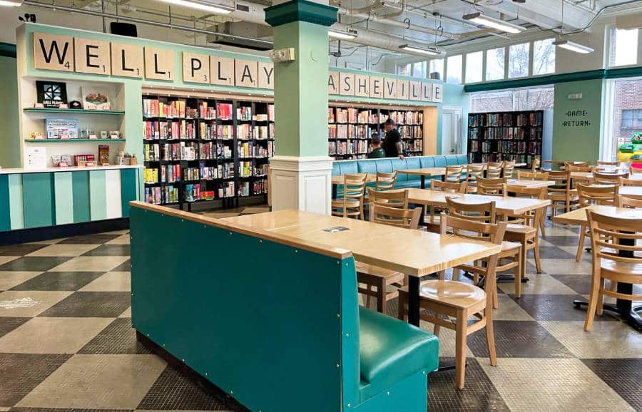 View of the empty chairs and tables and the displayed books and board games on the shelves inside the Well Played Board Game Cafe