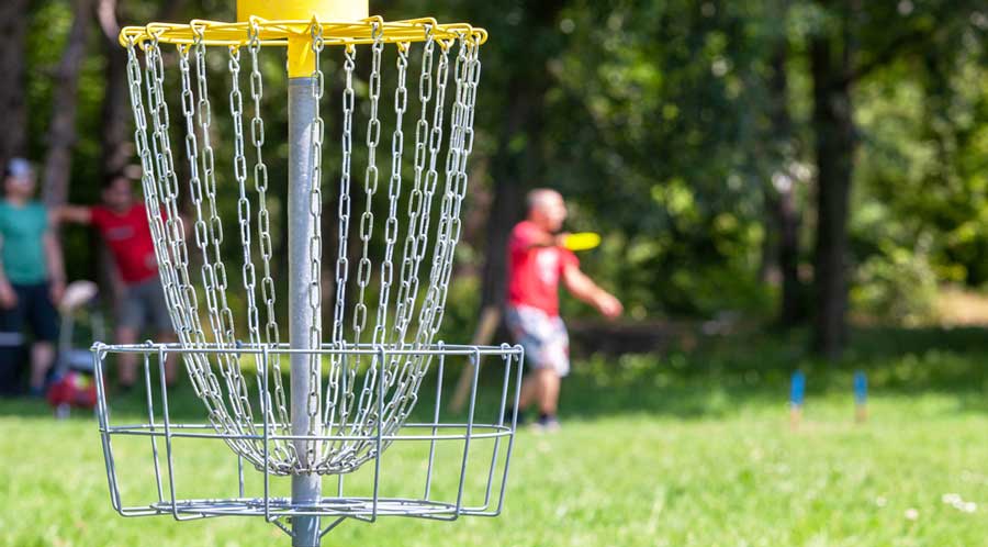 A man playing a flying disc golf during a sunny day