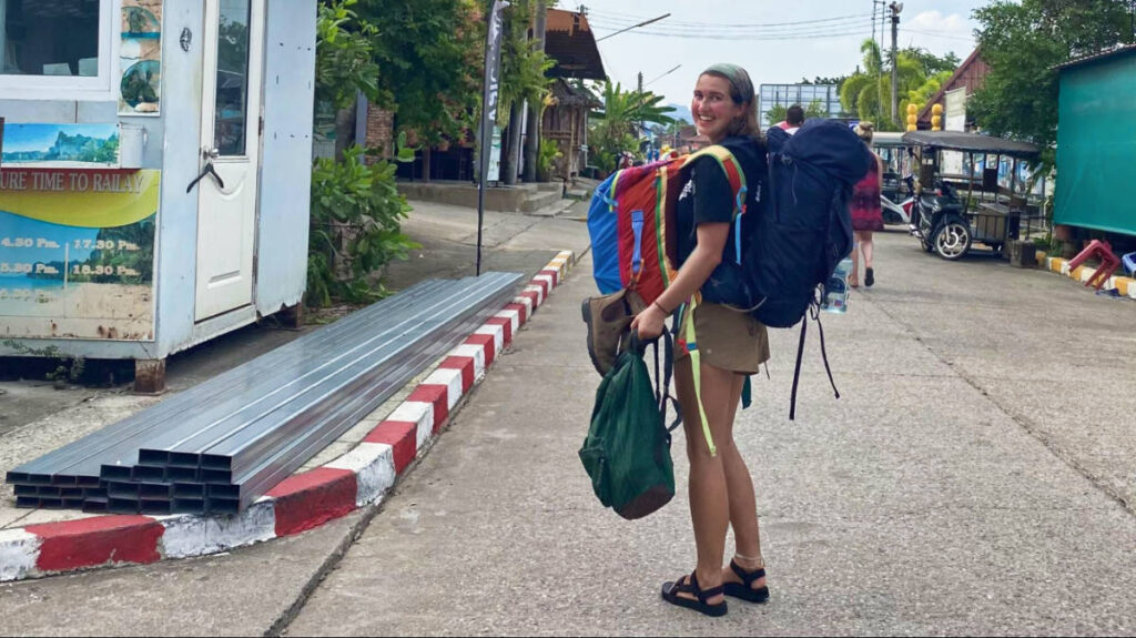 The author Laura McFarland carrying large multiple backpacks on her front and back in Thailand