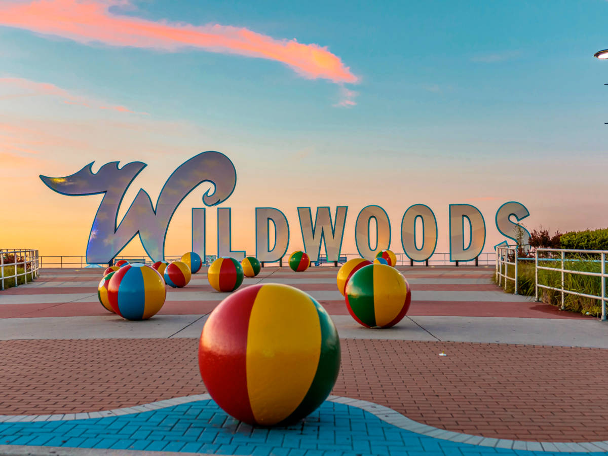 Entrance view with a big sign of Wildwoods boardwalk and large beachballs around at sunset