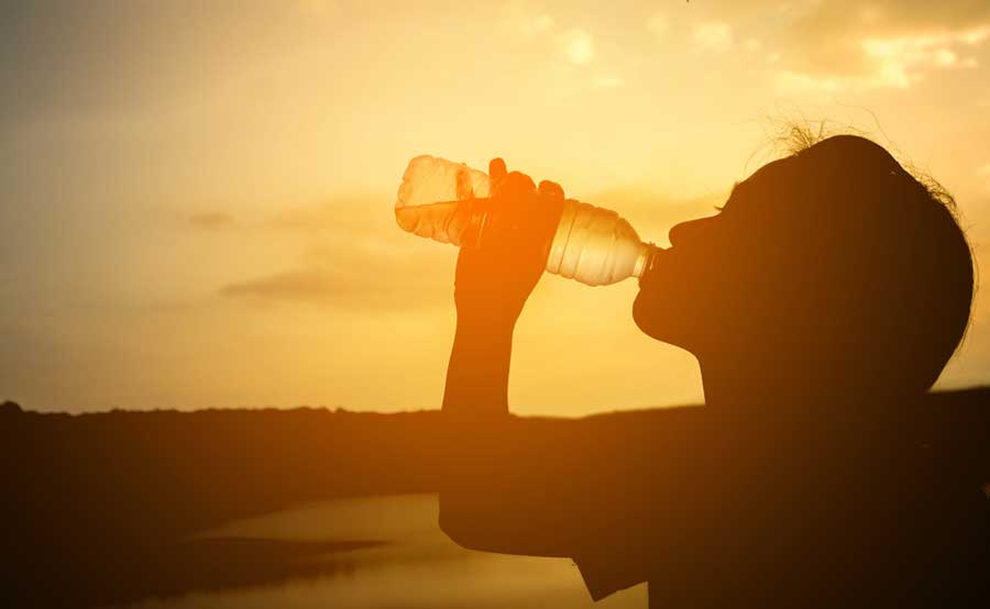 A silhouette of a woman drinking a bottle of water