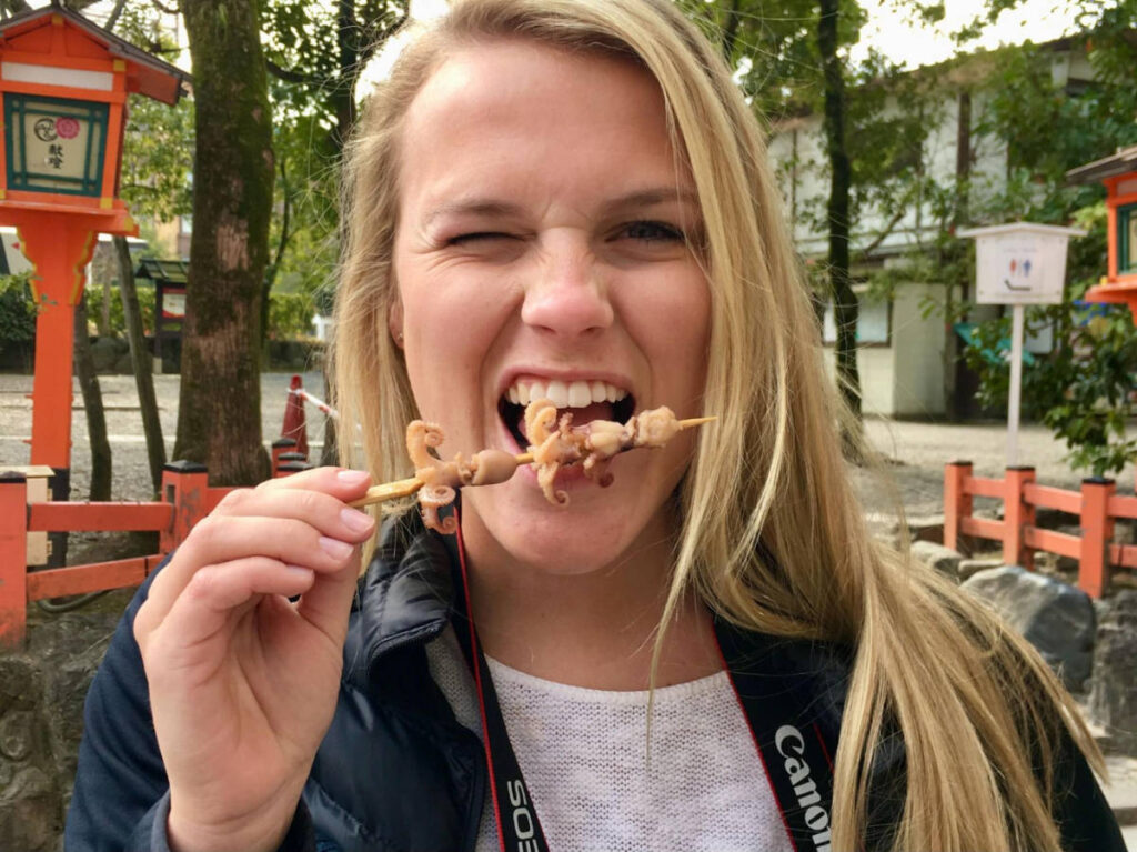 The author's friends taking a bite on the squid skewer