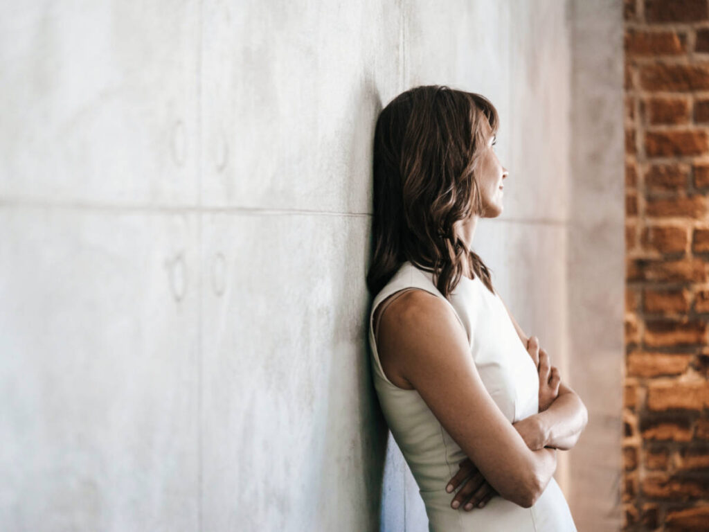 A woman leaning on the wall while crossing her arms