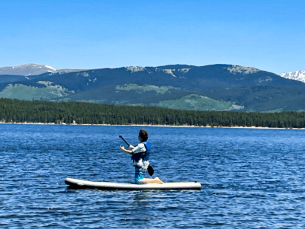 A woman paddleboarding in the middle of Turquoise Lake with scenic mountain view in the background