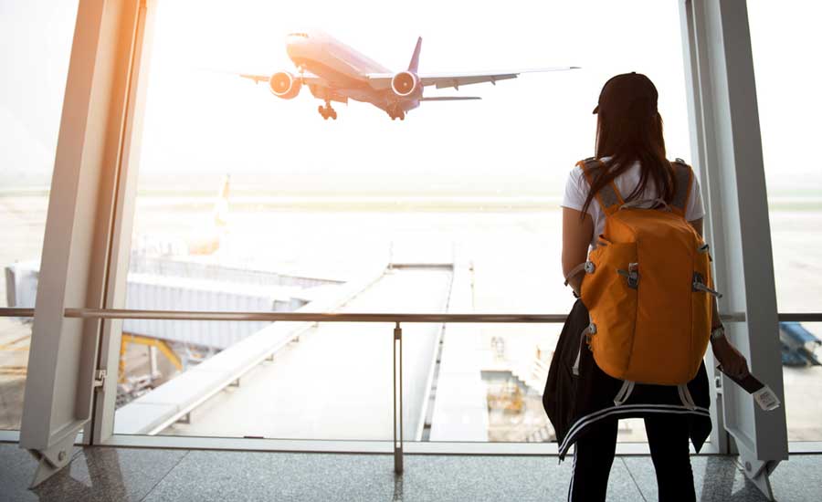 A woman with a backpack looking at the airplane