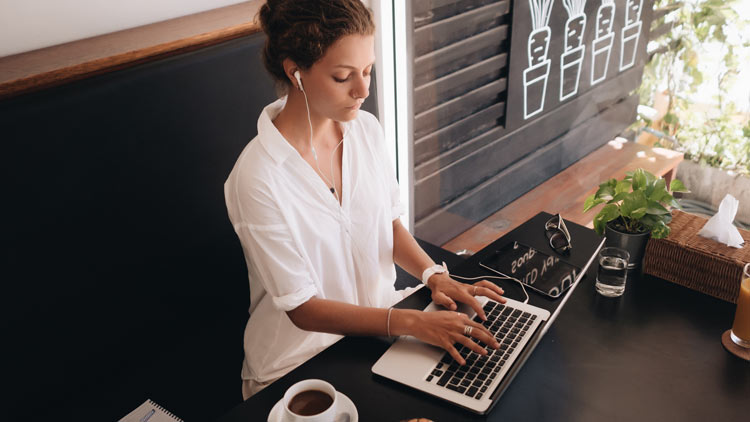 A woman working on the laptop with earphones